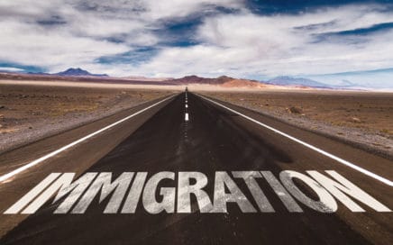 the word Immigration written on the road in the middle of the desert