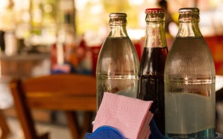 three glass soda bottles on a restaurant table
