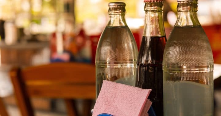 three glass soda bottles on a restaurant table