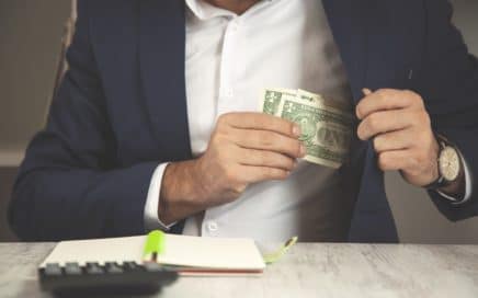 a man putting a few dollar bills into his blazer pocket