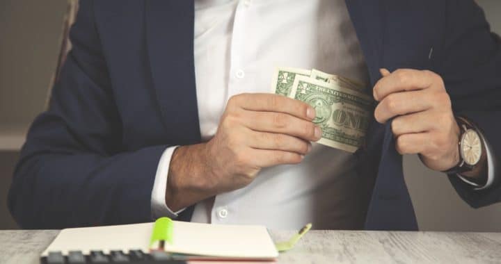 a man putting a few dollar bills into his blazer pocket